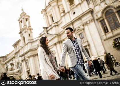 Casual young couple holding hands walking in Rome, Italy, Europe.