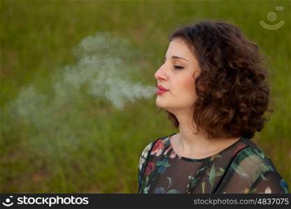 Casual young woman smoking a cigar in the landscape
