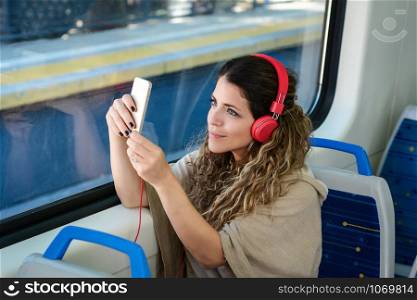 Casual young woman taking a selfie on train with her phone. Enjoying travel.