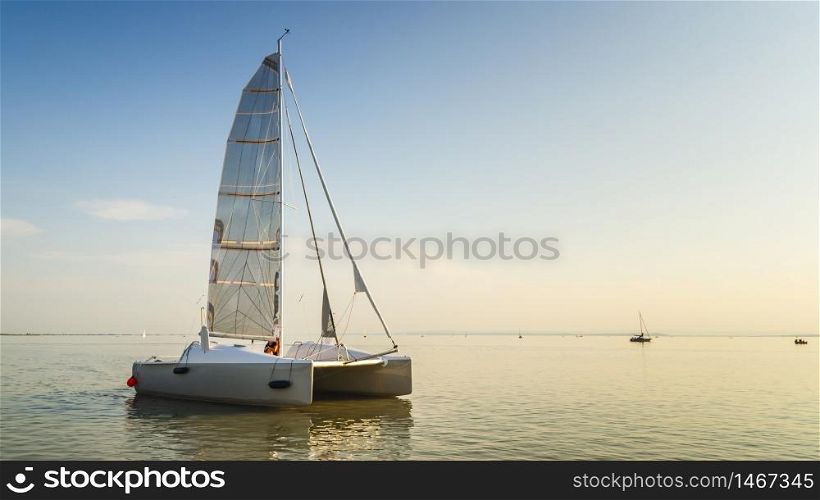 Catamaran boat on the Neusiedlersee lake in Austria. Clear sky calm water before sunset copy space. Catamaran boat on Neusiedlersee lake in Austria