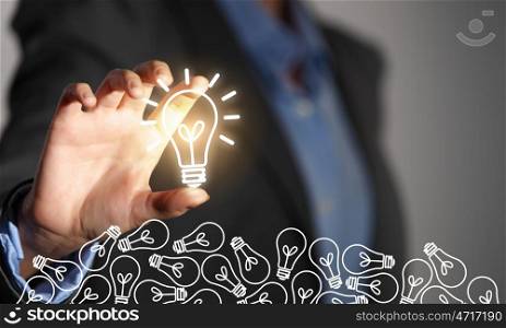 Catch bright idea. Close up of businesswoman taking glowing light bulb with fingers