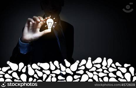 Catch bright idea. Young businessman taking glowing light bulb with fingers
