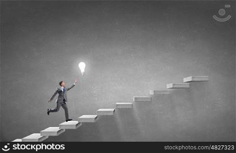 Catch your bright idea for promotion. Running young businessman trying to catch glowing light bulb
