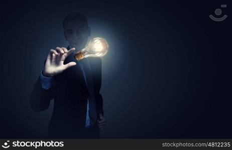 Catch your idea. Young businessman catching glass light bulb with finger