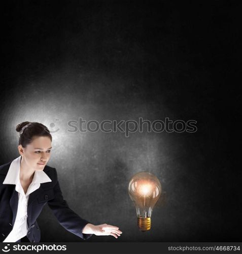 Catch your idea. Young businesswoman catching glass light bulb with fingers