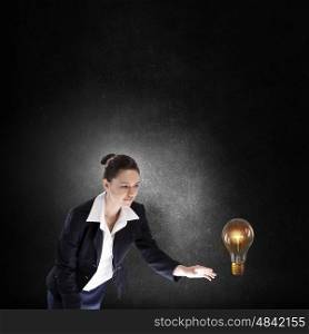 Catch your idea. Young businesswoman catching glass light bulb with fingers