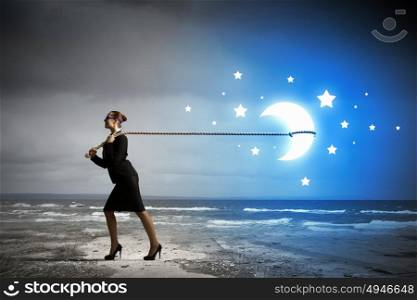 Catching moon. Image of businesswoman pulling moon with rope