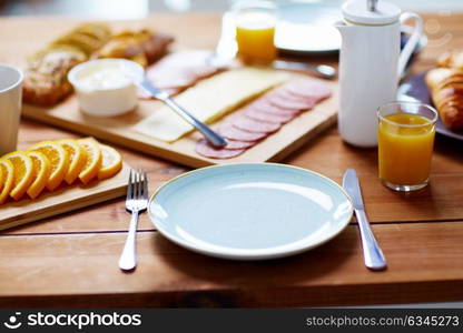 catering and eating concept - plate and glass of orange juice on wooden table with food. plate and glass of orange juice on table with food