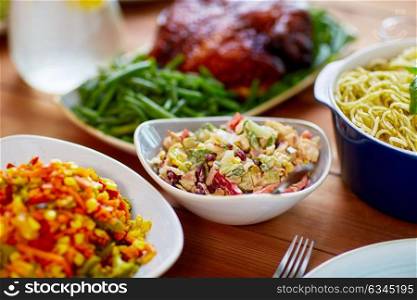 catering and eating concept - vegetable salad in bowl and other food on wooden table. vegetable salad in bowl and other food on table