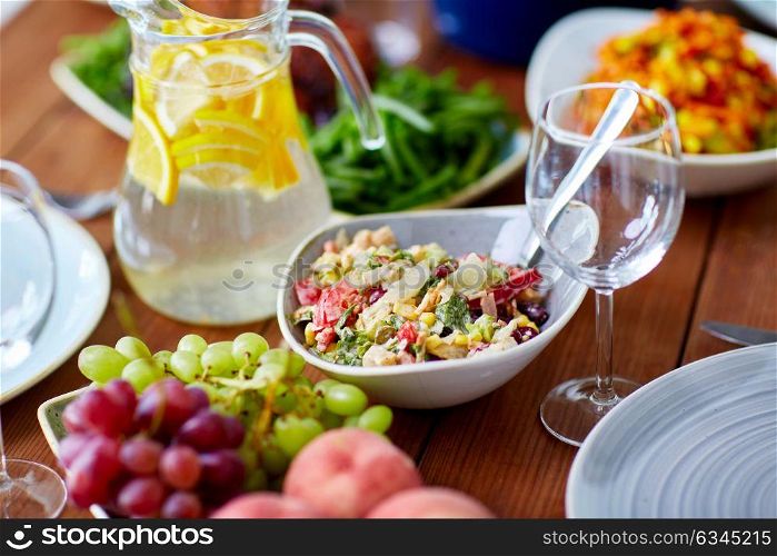 catering and eating concept - vegetable salad in bowl and other food on wooden table. vegetable salad in bowl and other food on table
