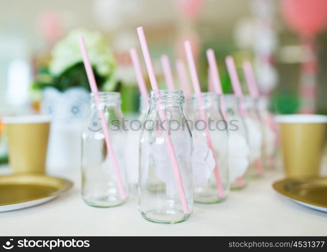 catering, dishware, holidays and celebration concept - closeup of glass bottles for drinks with straws on table