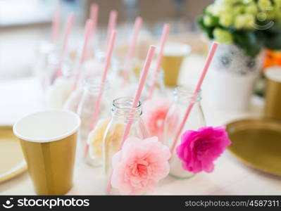 catering, dishware, holidays and celebration concept - closeup of glass bottles for drinks with straws on table