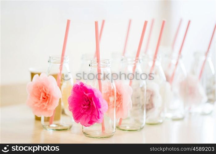 catering, dishware, holidays and celebration concept - closeup of glass bottles for drinks with straws on table