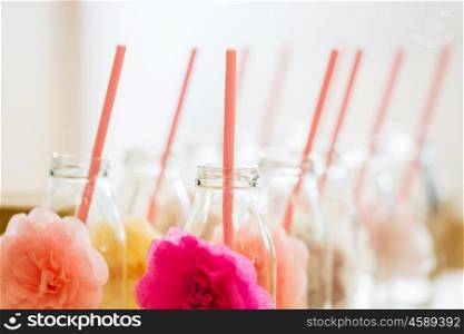 catering, dishware, holidays and celebration concept - closeup of glass bottles for drinks with straws
