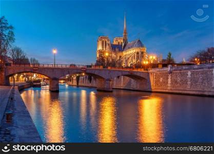 Cathedral of Notre Dame de Paris and bridge Pont de l'Archeveche, Archbishop's Bridge, as seen from Quai de la Tournelle during evening blue hour, Paris, France