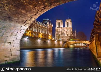 Cathedral of Notre Dame, Petit Pont and riverside of Seine river in Paris at night, France