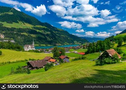 Catholic church, traditional wood and modern houses along the lake Lungernsee in swiss village Lungern in sunny summer day, Obwalden, Switzerland. Swiss village Lungern, Switzerland