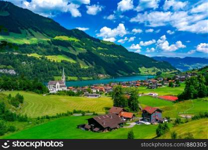 Catholic church, traditional wood and modern houses along the lake Lungernsee in swiss village Lungern, canton of Obwalden, Switzerland. Swiss village Lungern, Switzerland