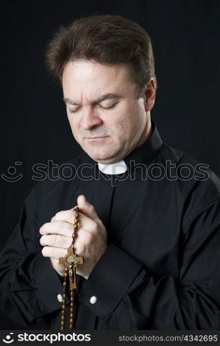 Catholic priest praying with his rosary beads.