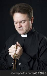 Catholic priest praying with his rosary beads.