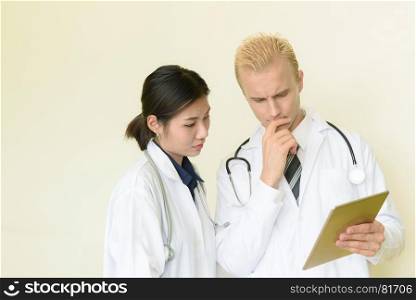 caucasian and asian doctor using digital tablet in hospital, selective focus