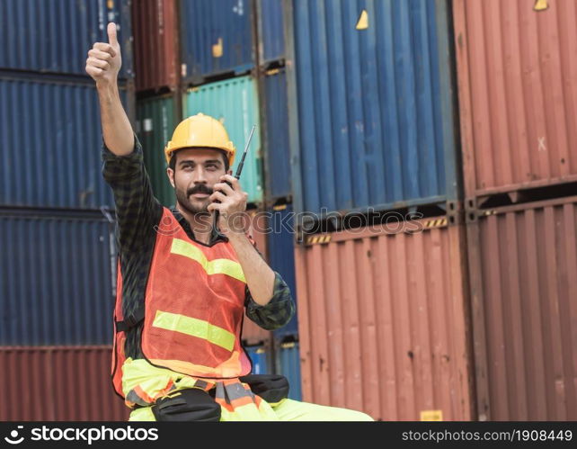 Caucasian beard foreman or Engineer wearing safety helmet and control for loading containers while talking on walkie talkie. Engineering and Shipping Concept.