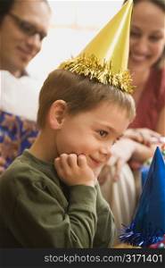 Caucasian boy at birthday party looking to the side and smiling.