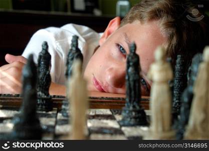 Caucasian Boy Looking Inquisitivey At A Chess Board