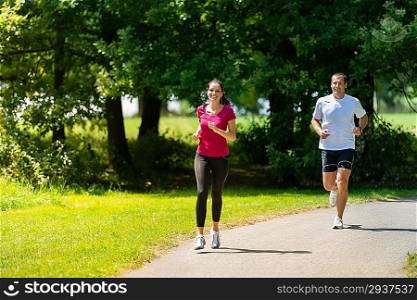 Caucasian boyfriend and girlfriend running a race in sunny park