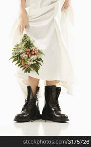 Caucasian bride holding bouquet down by her black combat boots.