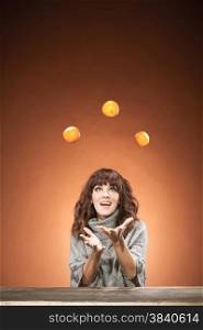 Caucasian brunette woman is juggling oranges