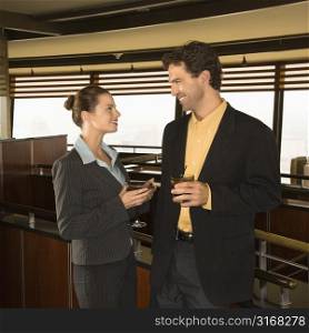 Caucasian business man and woman conversiting with alcoholic beverages.