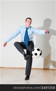 caucasian business man is playing football at office near gray wall