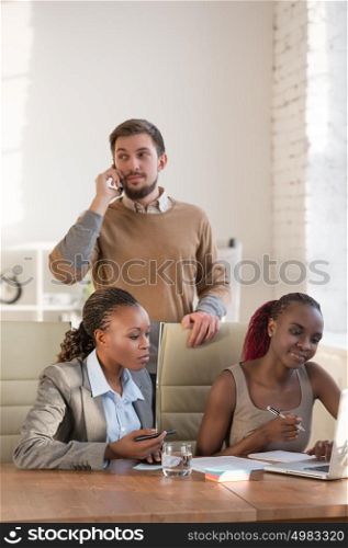 Caucasian business man working at office with his african colleagues. Office life concept