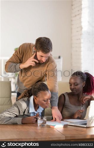 Caucasian business man working at office with his african colleagues. Office life concept