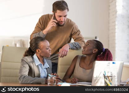 Caucasian business man working at office with his african colleagues. Office life concept