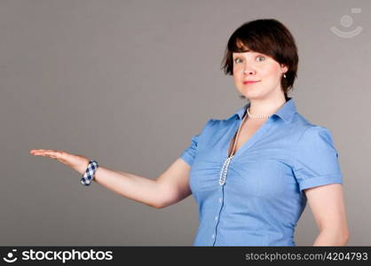 caucasian business woman is holding blank space on gray background