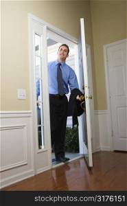Caucasian businessman at open door with briefcase.