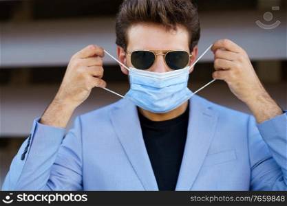 Caucasian businessman putting on a surgical mask to protect against the coronavirus.. Businessman putting on a surgical mask to protect against the coronavirus.