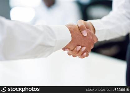 Caucasian businessman shaking hands with businesswoman wearing suit in a office. Close-up shot