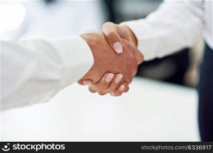 Caucasian businessman shaking hands with businesswoman wearing suit in a office. Close-up shot