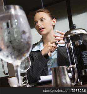 Caucasian businesswoman sitting at table with coffee and beverages.