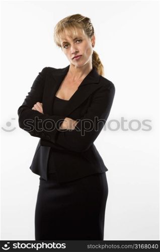 Caucasian businesswoman standing with arms crossed and giving stern expression to viewer.