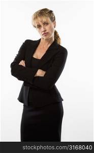 Caucasian businesswoman standing with arms crossed and giving stern expression to viewer.