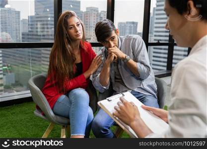 Caucasian couple sitting on the chair in the psychiatrist room to consult mental health problems by doctor, Health and illness concepts