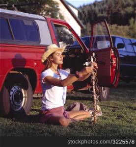 Caucasian Cowgirl Sitting In Front Of A Red Pickup Truck And Holding A Decorated Stick