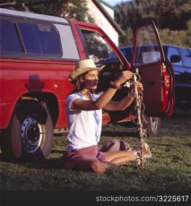 Caucasian Cowgirl Sitting In Front Of A Red Pickup Truck And Holding A Decorated Stick
