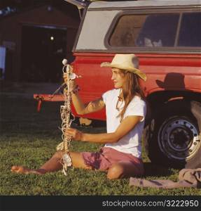 Caucasian Cowgirl Sitting Next To A Pickup And Holding A Decorated Stick