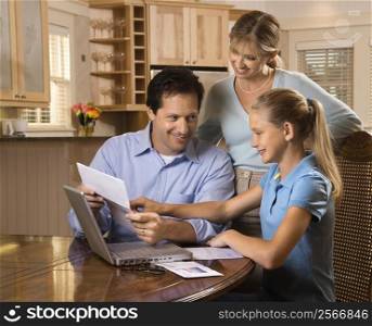 Caucasian family paying bills on laptop computer.