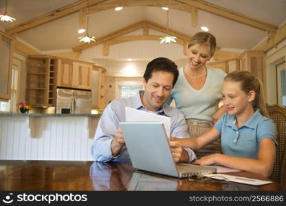 Caucasian family paying bills on laptop computer.